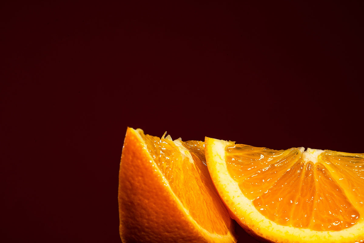 Fresh orange wedges against a deep red background