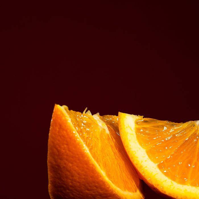 Fresh orange wedges against a deep red background