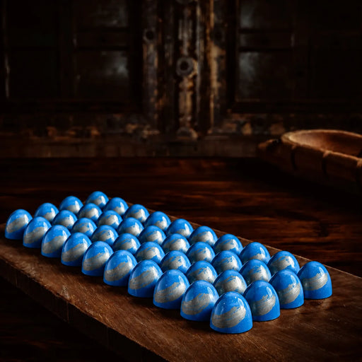 A row of small blue and white marbled chocolate bonbon coffee bon bon arranged on a wooden board in a dark rustic setting.